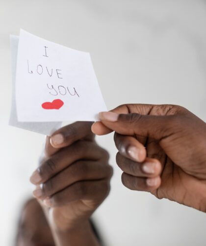 Black Female Hand Putting Sticky Note With Love Message On Mirror, Closeup
