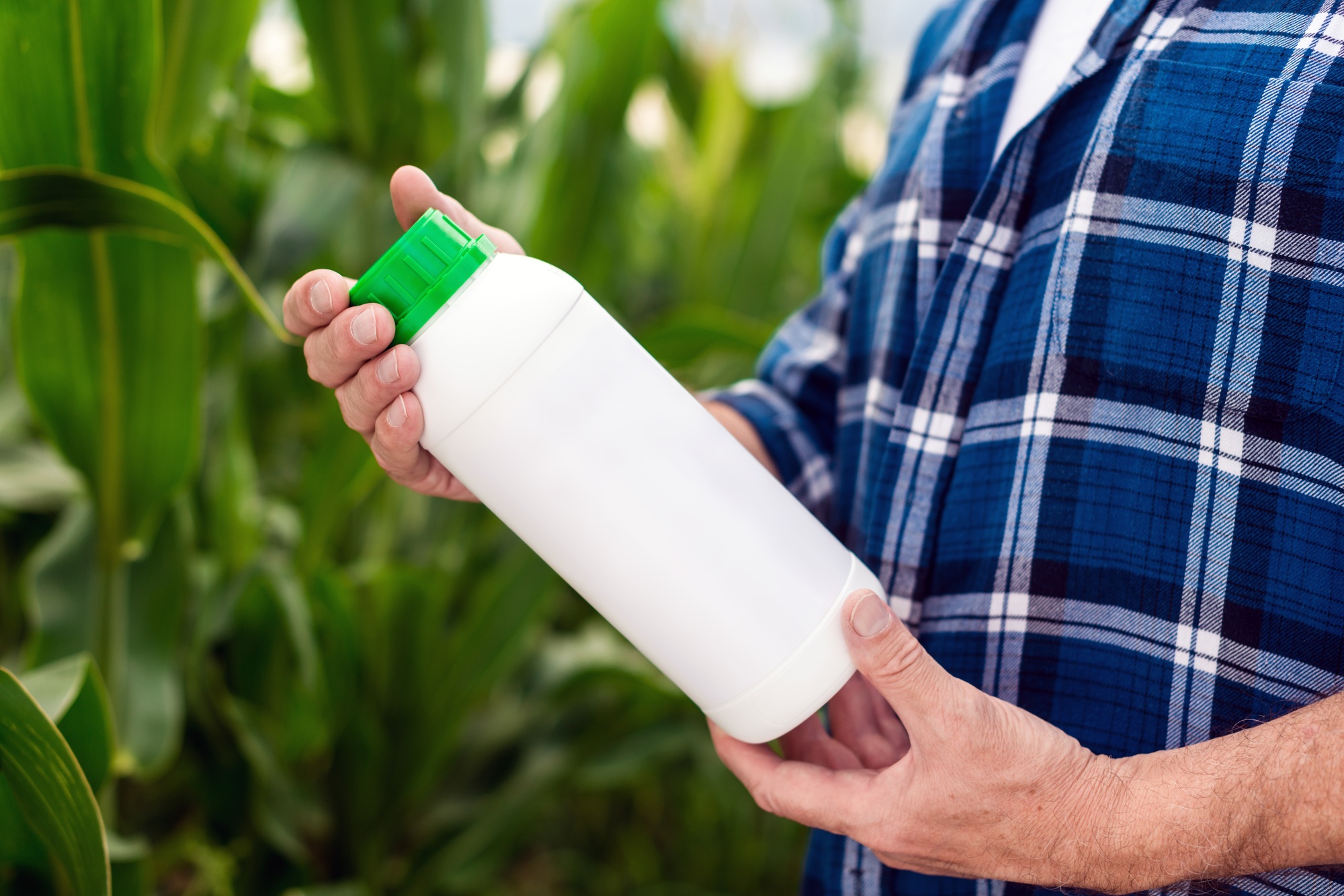 Closeup the bottle with chemical fertilizers in the hands of middle aged agronomist