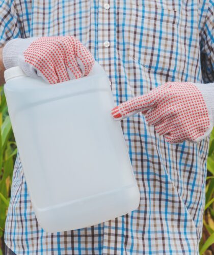 Farmer holding pesticide chemical jug in cornfield