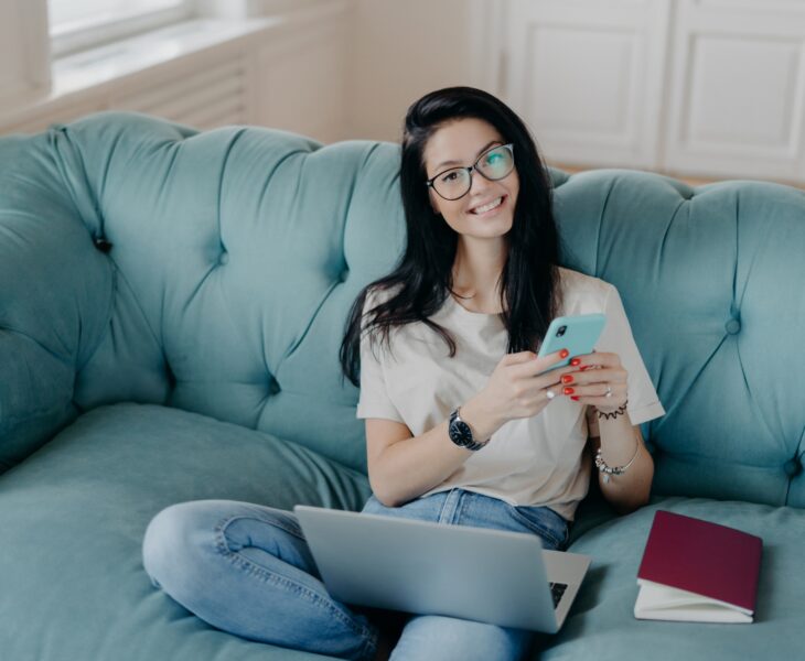Beautiful woman in transparent glasses and casual clothes, sends files, browses social networks