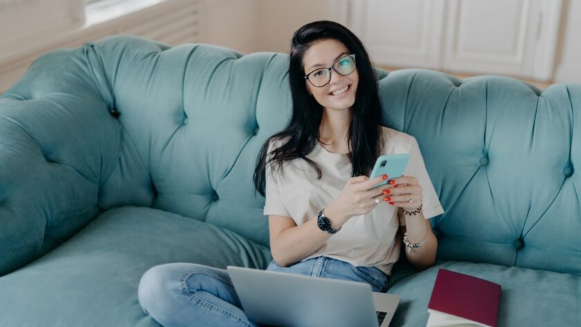 Beautiful woman in transparent glasses and casual clothes, sends files, browses social networks