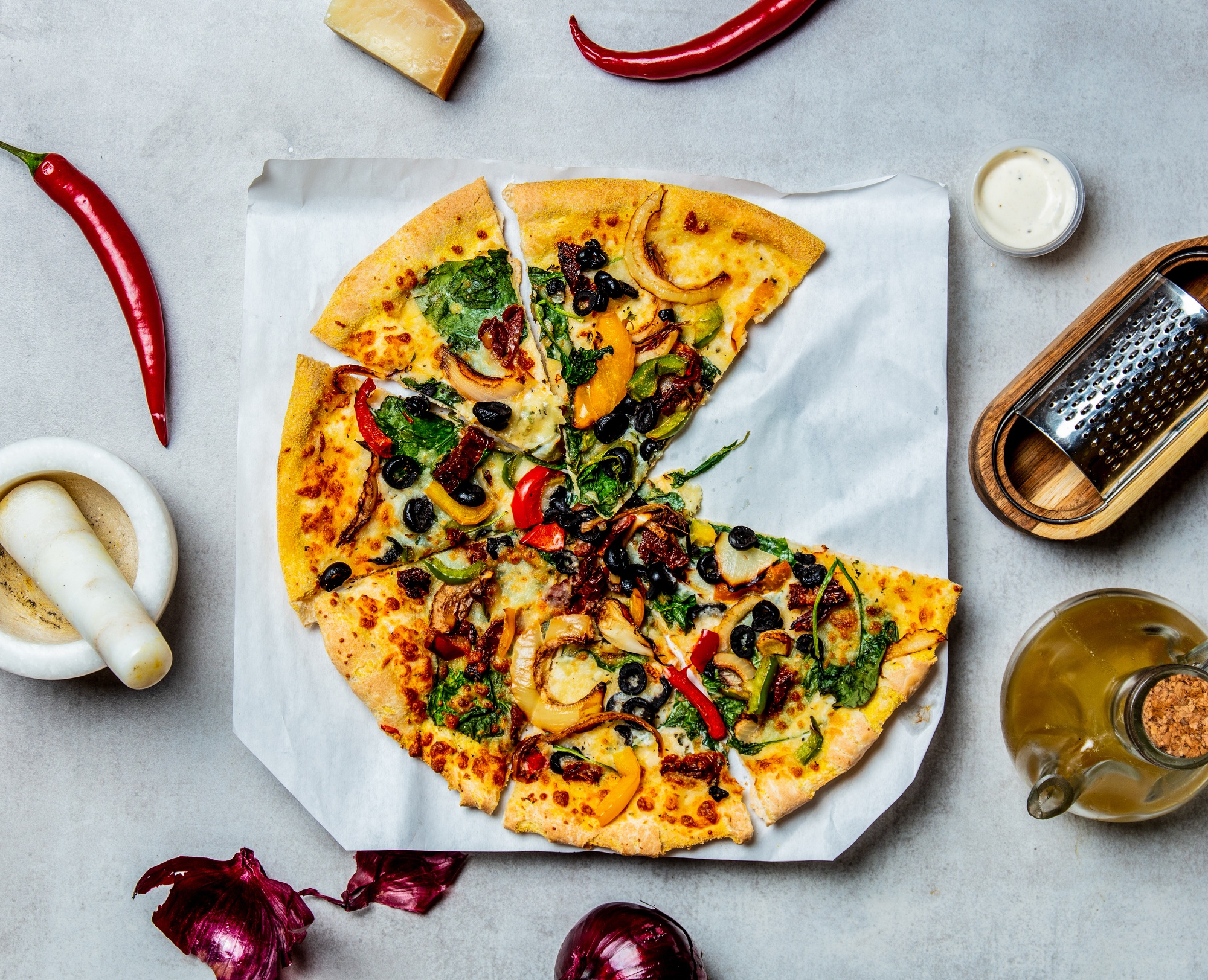 mediterranean Pizza with olives and cheese and ingredients around