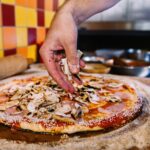 Putting Mushrooms On Pizza In Pizza Restaurant
