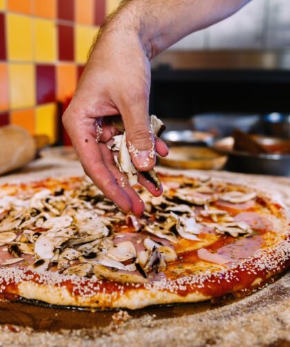 Putting Mushrooms On Pizza In Pizza Restaurant