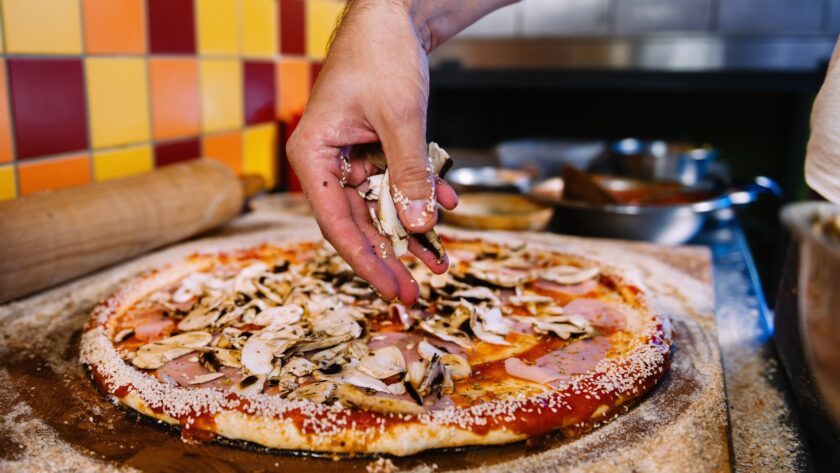 Putting Mushrooms On Pizza In Pizza Restaurant